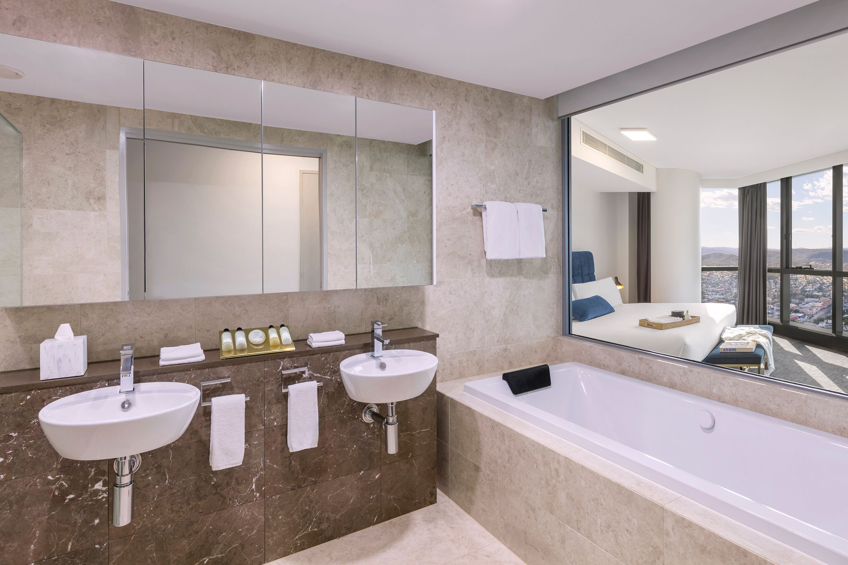 A modern bathroom with two sinks, a large mirror, and a bathtub.
