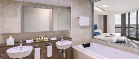 A modern bathroom with two sinks, a large mirror, and a bathtub.