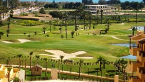 Un campo de golf con vistas al mar y montañas al fondo.