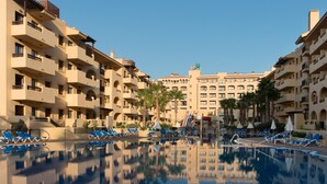 Un hotel con varios balcones, piscina y palmeras.