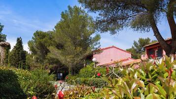 A garden with a red building, surrounded by trees and shrubs.
