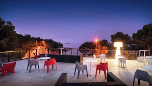 An outdoor patio with seating and tables, overlooking a body of water and trees.