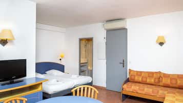 A hotel room with a bed, a desk with a television, a sofa, and two wall-mounted lamps.