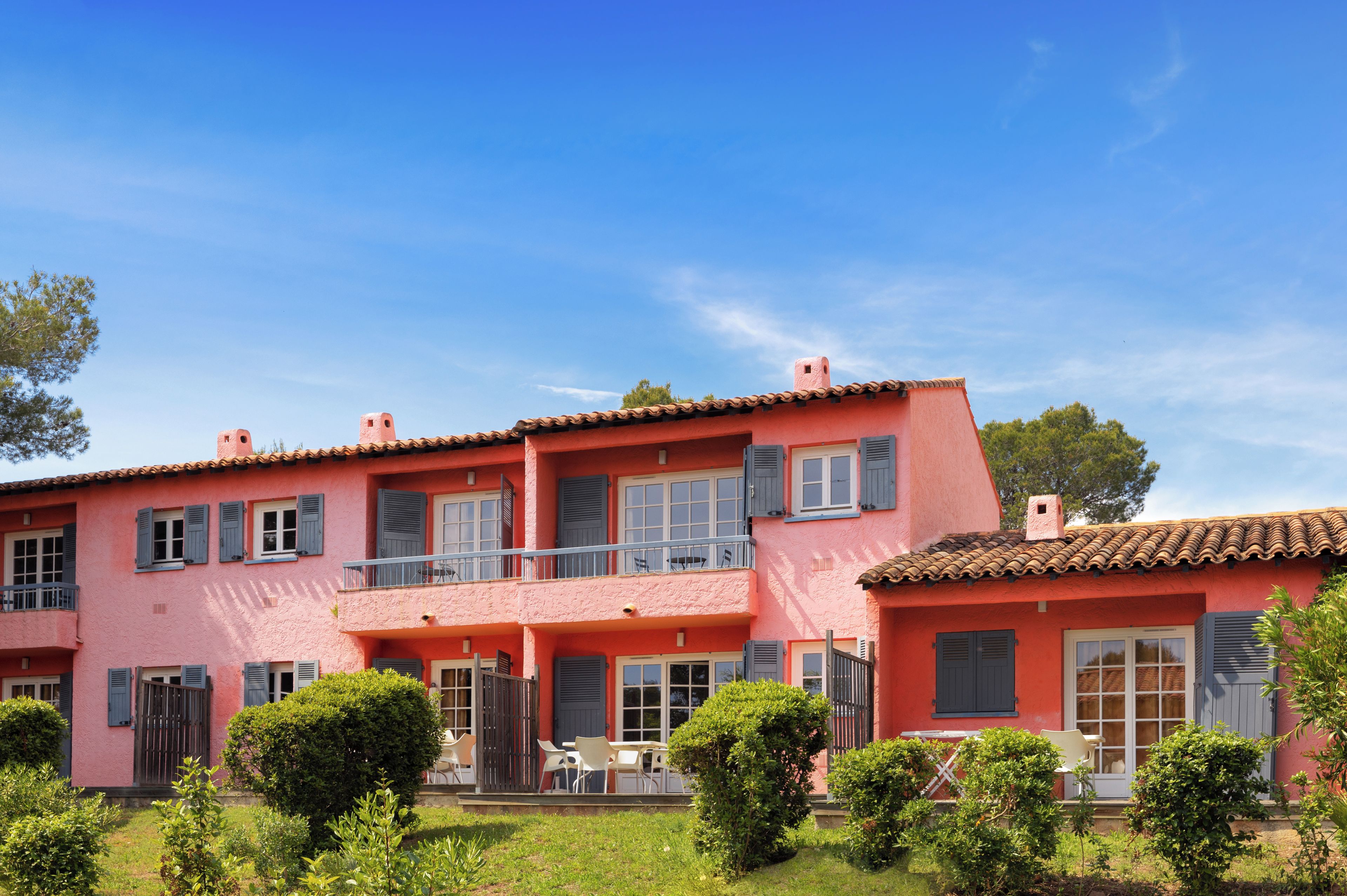 A two-story building with a balcony and a small garden area.