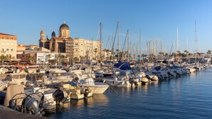A marina with numerous boats docked, a prominent church with domes, and a Ferris wheel in the background.
