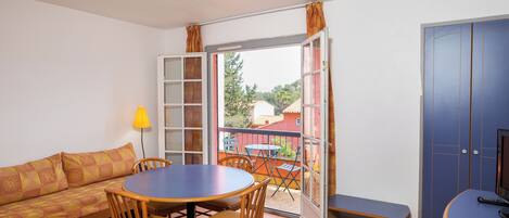 A room with a sofa, a round table with chairs, a bench, and a TV.