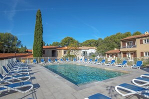 A swimming pool with lounge chairs and a tall tree. - Sowell Residences Les Chenes Verts (Saint-Raphael)