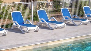 A swimming pool with clear blue water and lounge chairs along the edge.