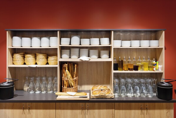 A kitchen counter with shelves stocked with plates, baskets, and glassware.