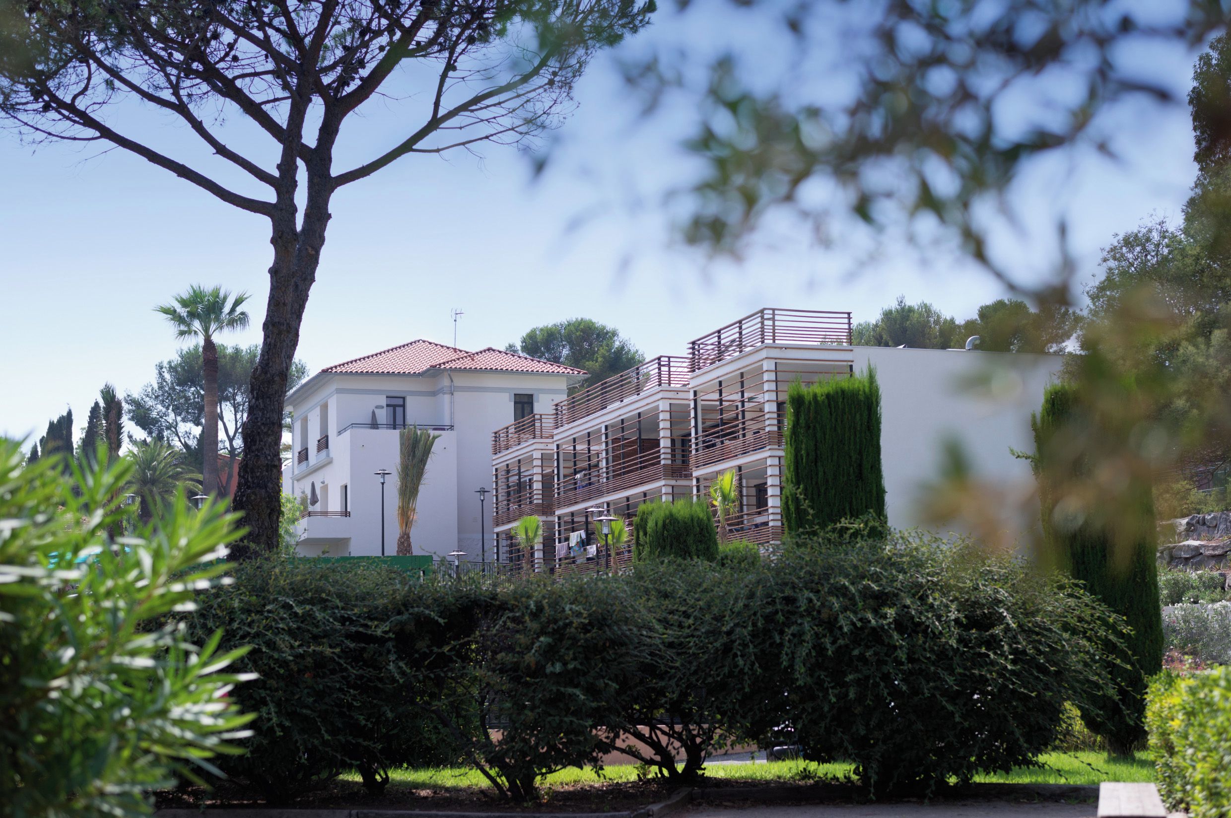 A modern building with multiple balconies and a garden area.