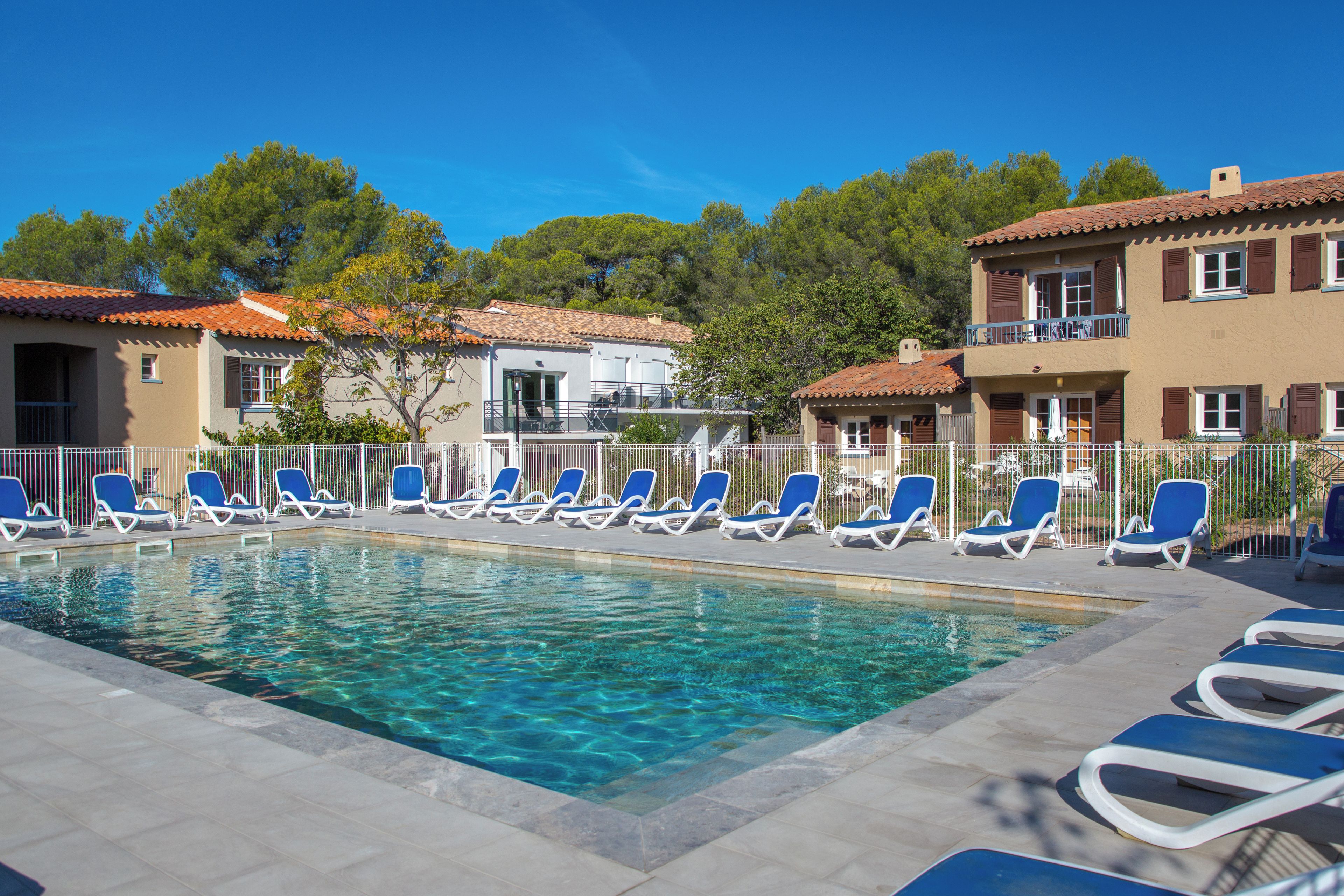 Una piscina con lettini da sole e un edificio con tetto in tegole.