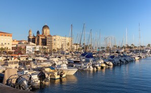 A marina with numerous boats docked, a prominent building with domed architecture, and a clear blue sky. - Sowell Residences Les Chenes Verts (Saint-Raphael)
