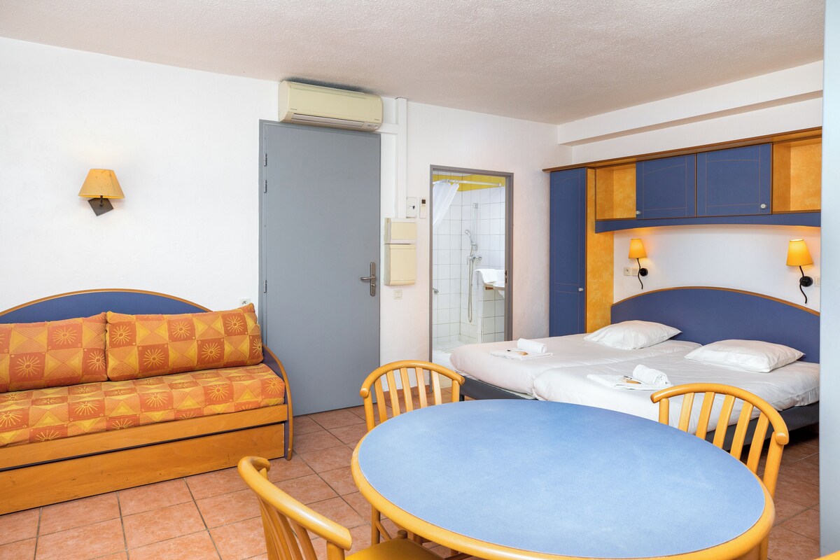 A room with a bed, a sofa, a table, and chairs.