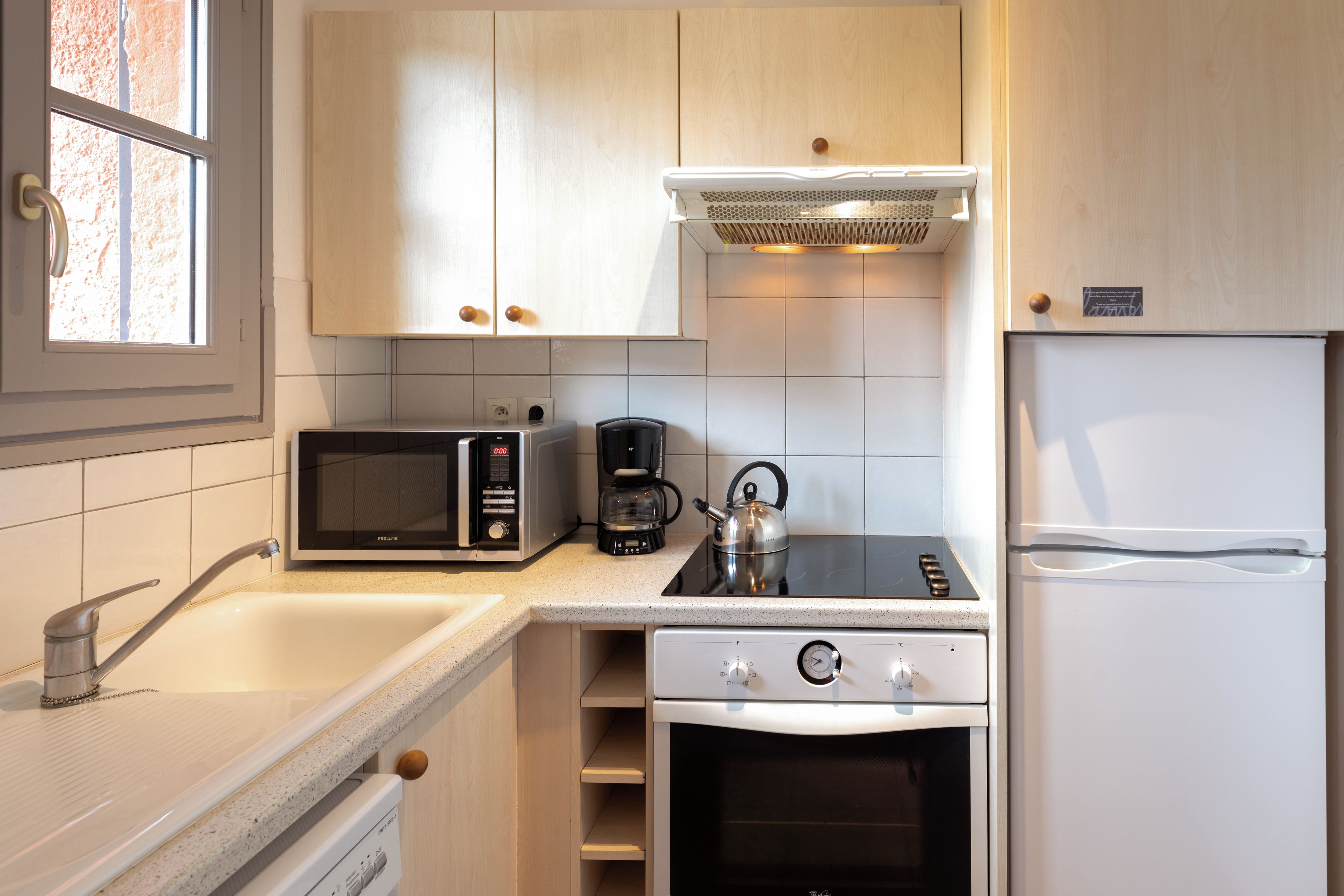 Una cucina moderna accessoriata con microonde, macchina del caffè, bollitore, fornello, forno e frigorifero.
