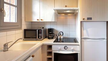 A modern kitchen with a microwave, coffee maker, kettle, stove, oven, and refrigerator.