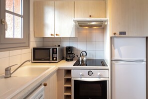 Una cucina moderna accessoriata con microonde, macchina del caffè, bollitore, fornello, forno e frigorifero.