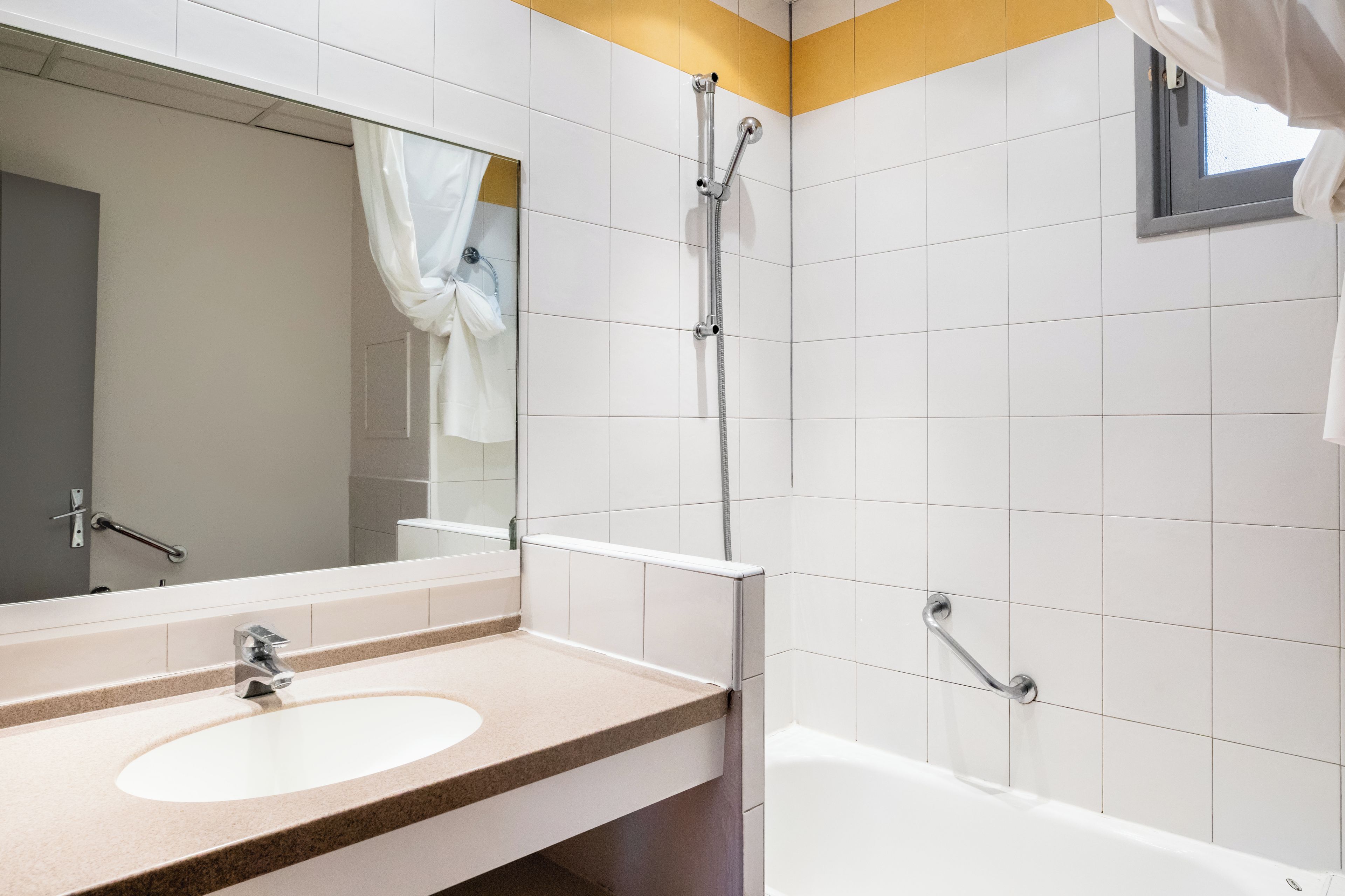 Un baño moderno con lavamanos, espejo, ducha y bañera.