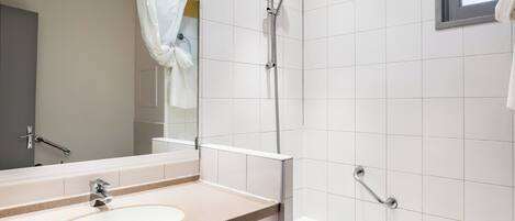 Un baño moderno con lavamanos, espejo, ducha y bañera.