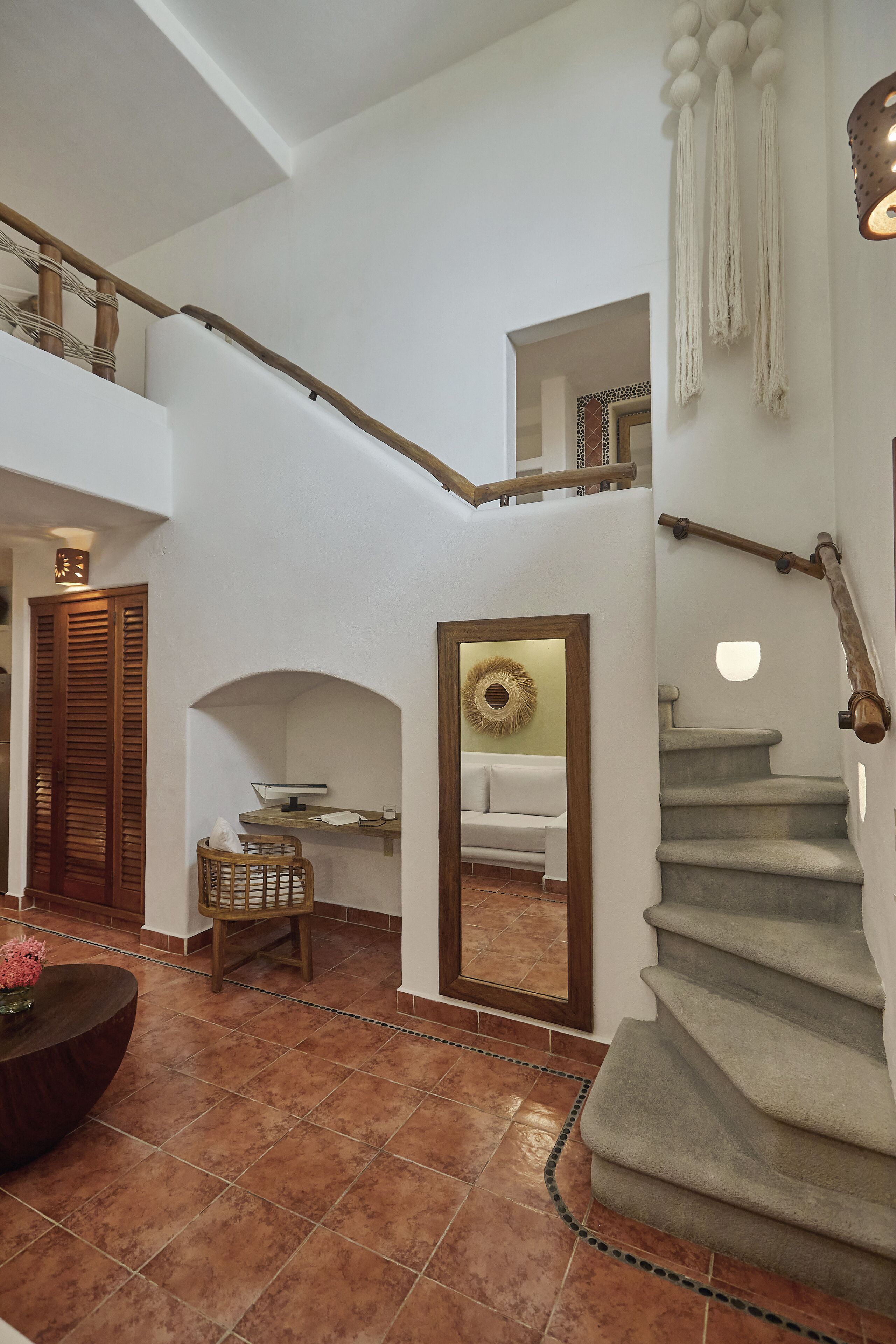 A multi-level interior with a staircase, wooden furniture, and a mirror.