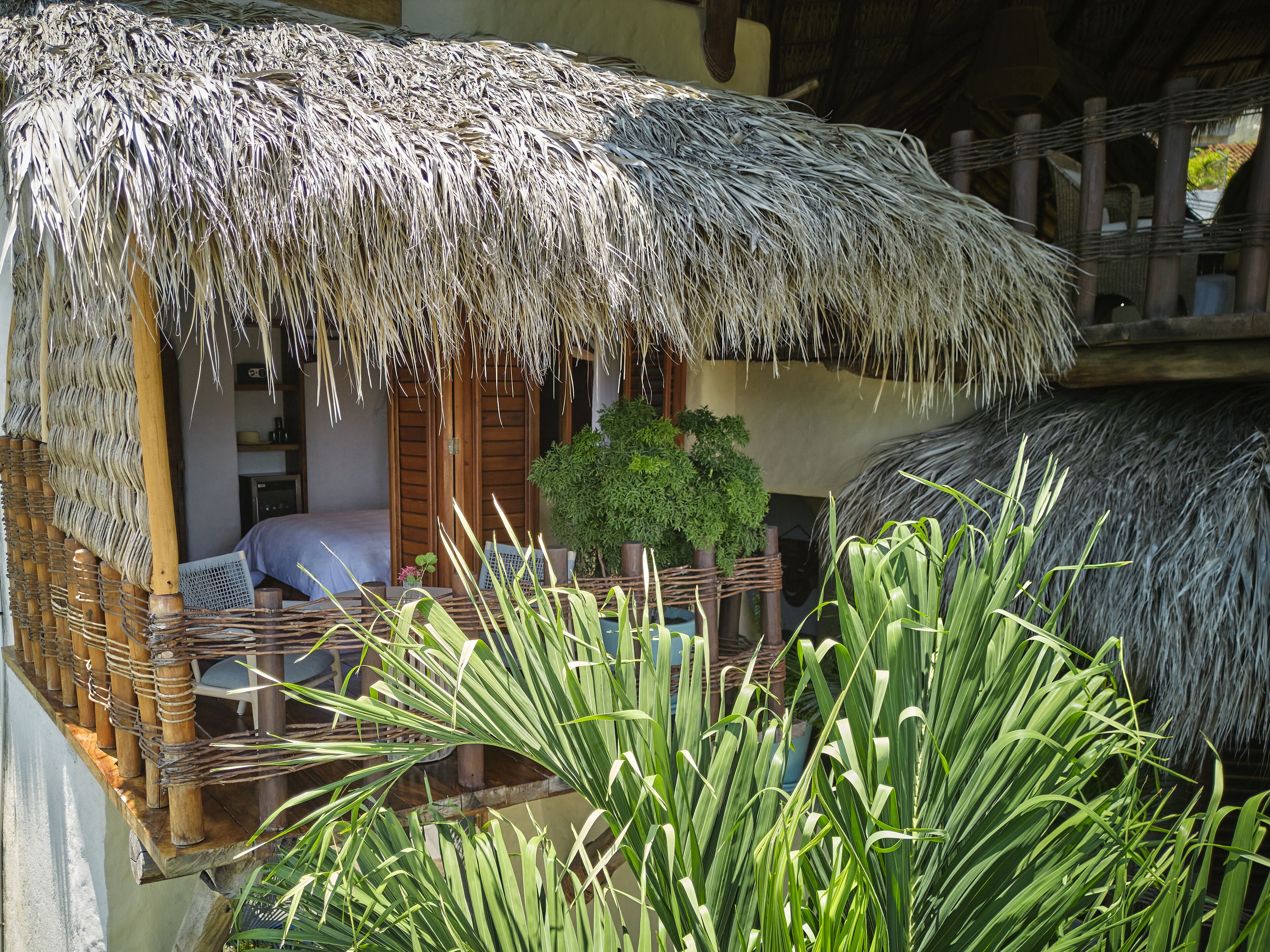 Un área de estar al aire libre con techo de paja, muebles de mimbre y una planta en maceta.
