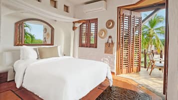 Un dormitorio con una cama grande, un espejo, contraventanas de madera y vistas al exterior.