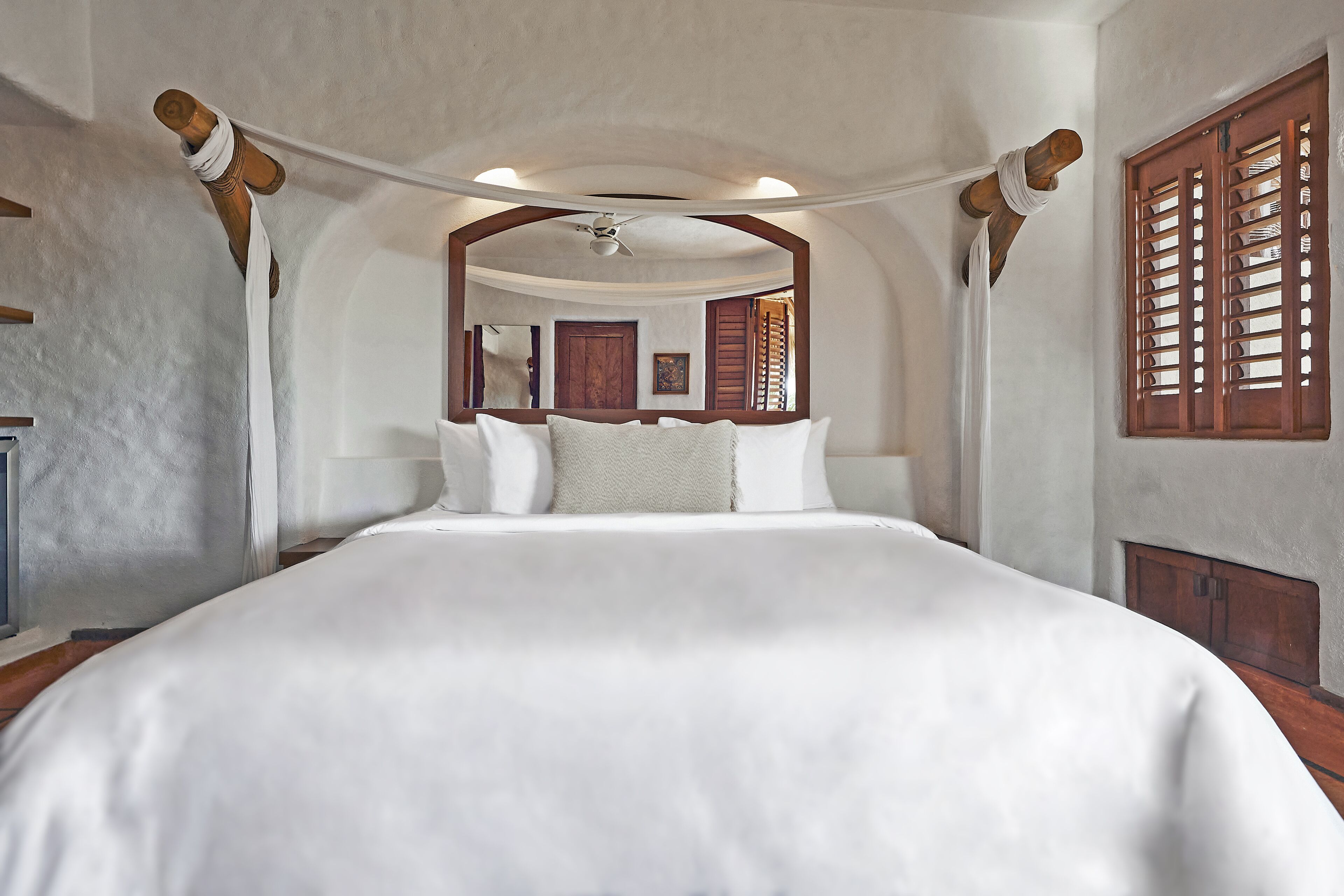 A bedroom with a large bed, wooden headboard, and a ceiling fan.