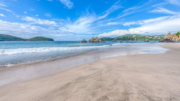 Een strand met heldere lucht en rustig water.