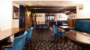 Ein Restaurantinnenraum mit Holztischen und blau gepolsterten Sitzbänken, Steinwänden und einem gemusterten Teppich.