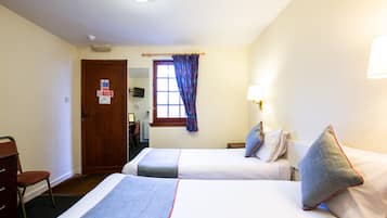Habitación de hotel con dos camas, un escritorio, una silla, ventana con cortinas y televisor montado en la pared.