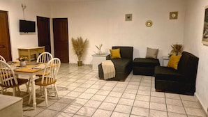 A living room with a dining area, a sofa set, a TV, and a ceiling fan. - Hotel Costa Brava (Manzanillo)