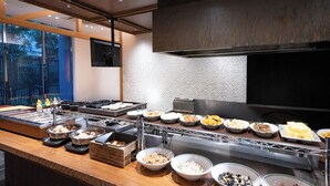 A buffet with various dishes, a kitchen area, and a view of trees through large windows. - APA Hotel Sugamo Ekimae (Tokyo)