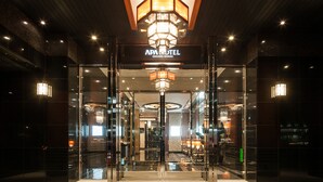 The entrance of a hotel with a glass facade, a central chandelier, and a sign above the doors. - APA Hotel Sugamo Ekimae (Tokyo)