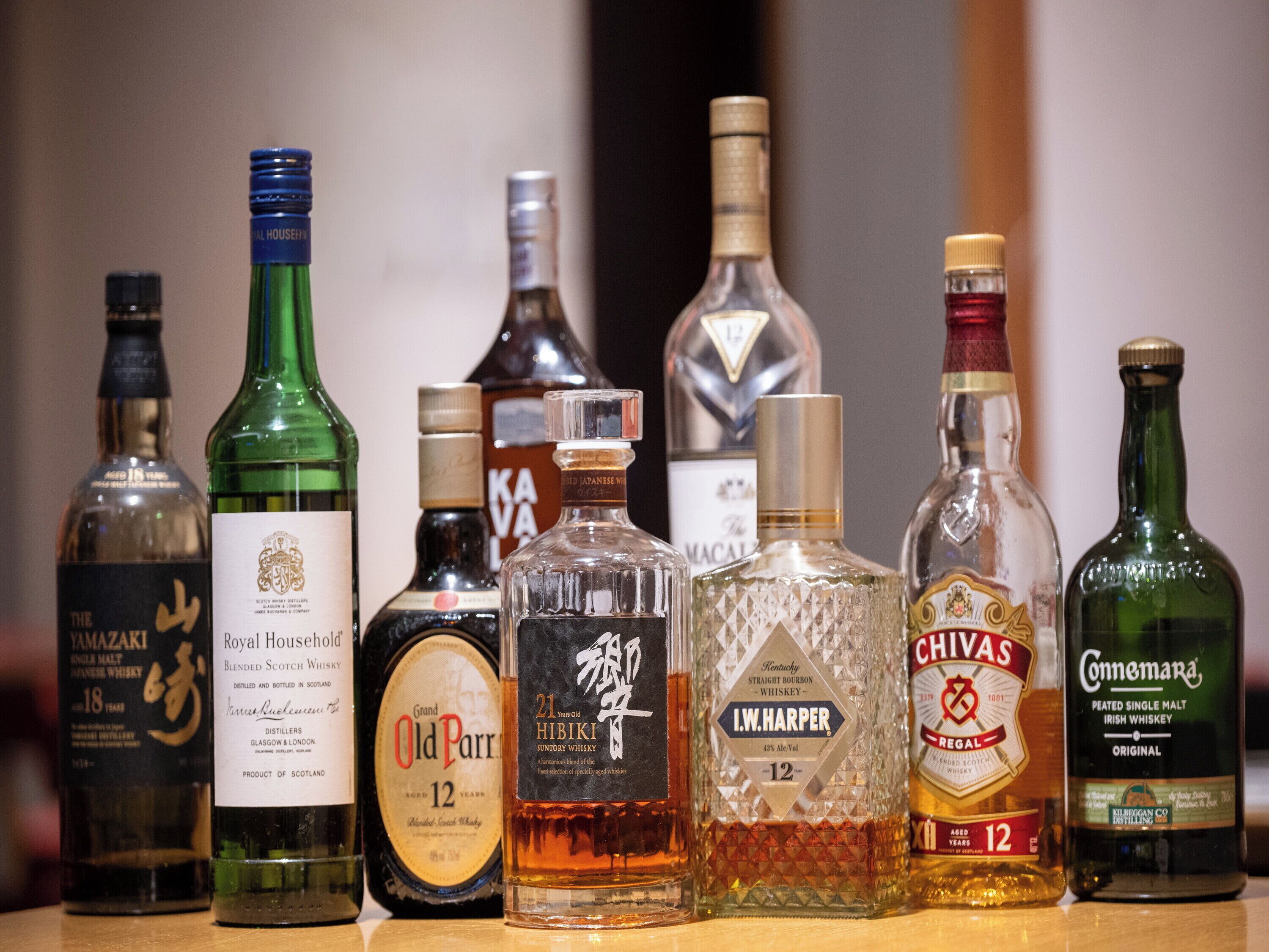 A variety of whiskey bottles displayed on a shelf.