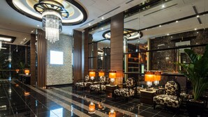 A lobby with a chandelier, seating area, and a large mirror reflecting the interior. - APA Hotel Sugamo Ekimae (Tokyo)
