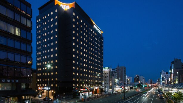 A multi-story hotel with a prominent 'APA' sign, a well-lit facade, and a busy street in the background. - APA Hotel Sugamo Ekimae (Tokyo)
