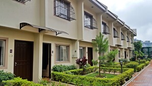 A row of modern hotel rooms with balconies, neatly arranged garden beds, and a clear view of the surrounding area. - Baguio Holiday Villas (Baguio)