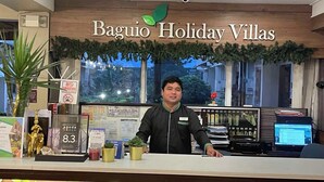 A reception desk at Baguio Holiday Villas with a wooden backdrop, a 'No Smoking' sign, and a 'BIR' sign. - Baguio Holiday Villas (Baguio)