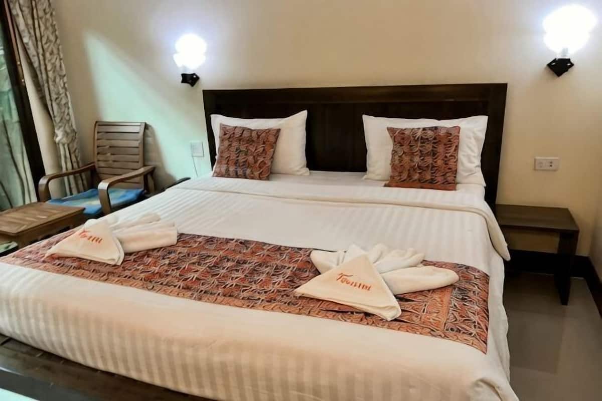 A hotel room with two beds, a wooden headboard, a nightstand, a chair, and a lamp.