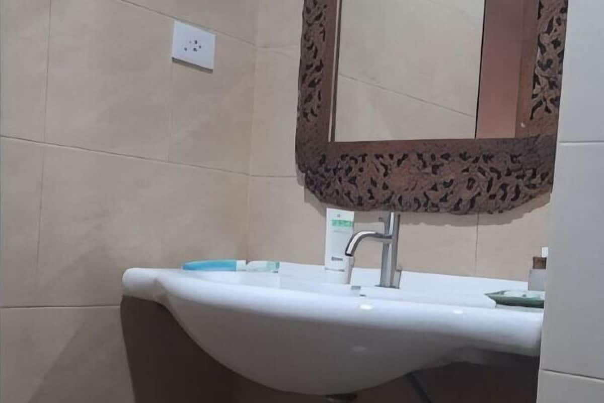 A bathroom with a white sink, a mirror with a decorative frame, and a towel rack.