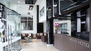 Eine moderne Hotelhalle mit Empfangstresen, Sitzgelegenheiten und Glasgeländern.