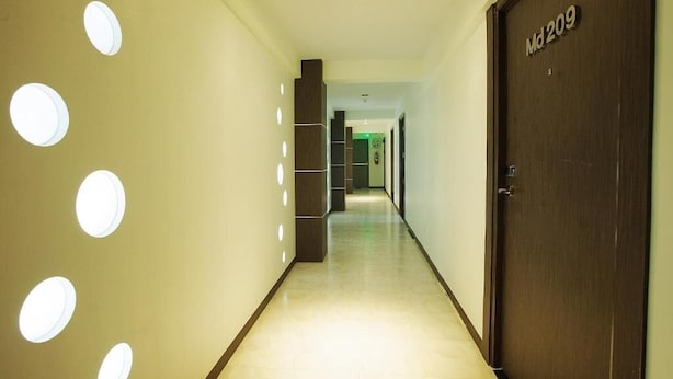 Ein Hotelgang mit einer Holztür mit der Aufschrift "Md 209", einem gefliesten Boden und runden Leuchten an der Wand.