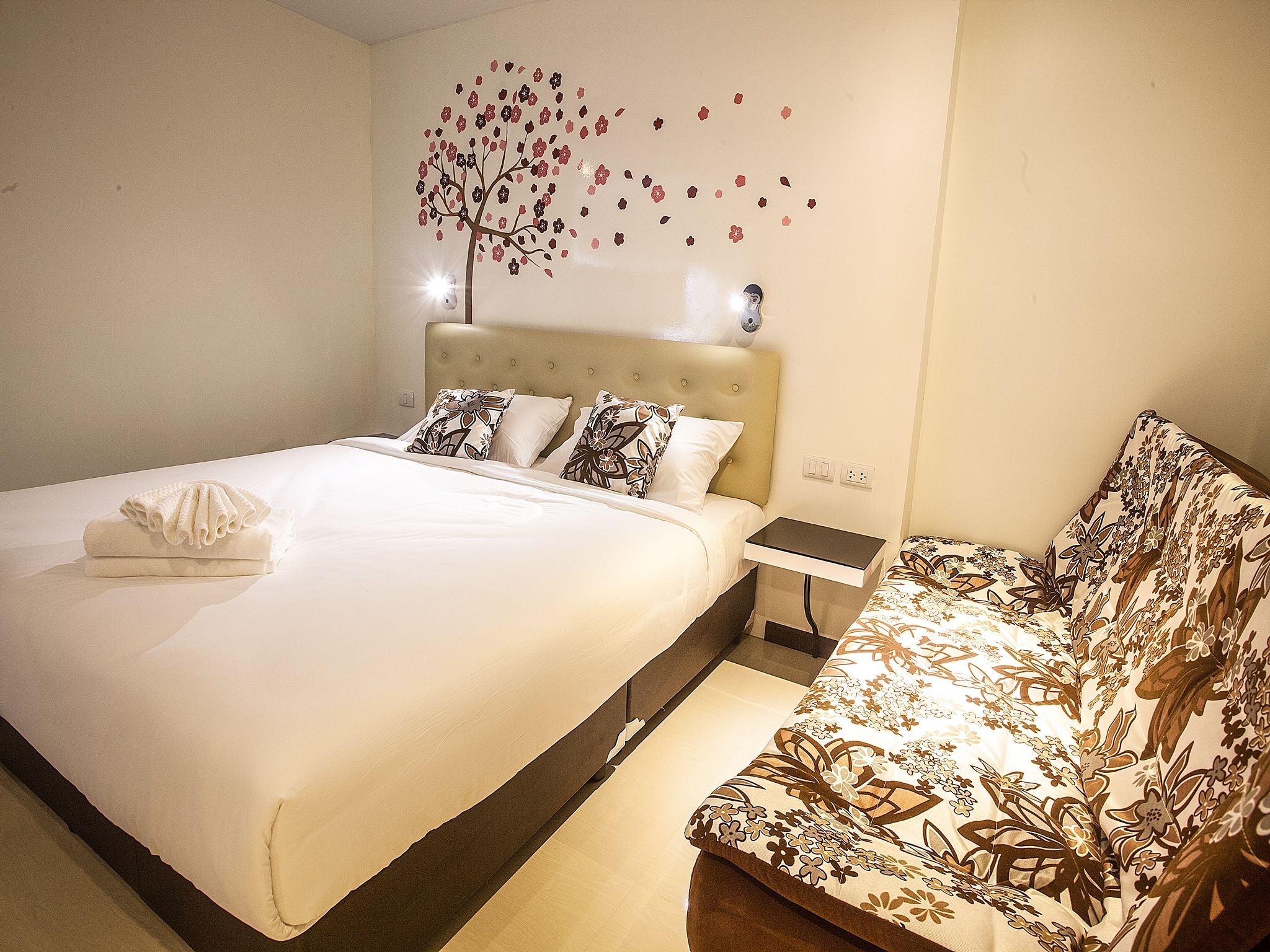 Una habitación de hotel con cama, mesita de noche, una silla y un adorno en la pared.