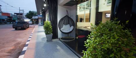 Un edificio moderno con fachada de vidrio, una silla colgante y plantas en macetas.