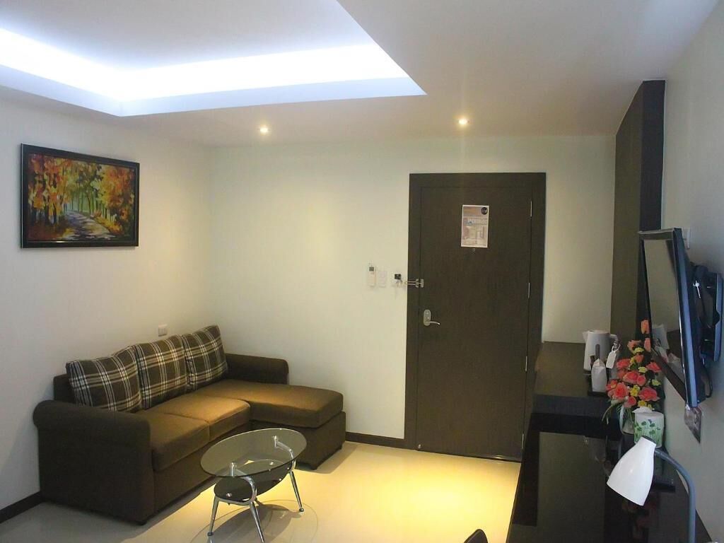 A modern living room with a sofa, a glass coffee table, a door, and a painting on the wall.