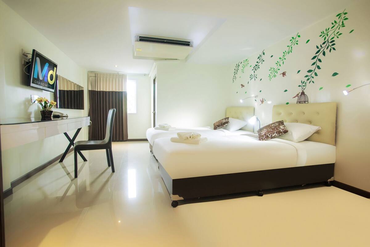 Habitación de hotel con una cama, un escritorio con computadora, una silla y un televisor en la pared.