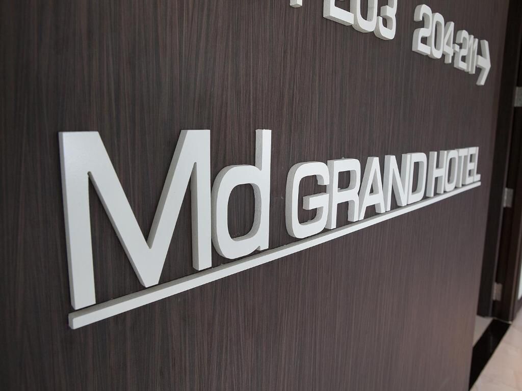 A sign for the Md GRAND HOTEL with a modern design, featuring the hotel's name and a directional arrow indicating the location.