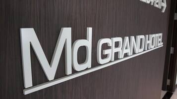 A sign for the Md GRAND HOTEL with a modern design, featuring the hotel's name and a directional arrow indicating the location.