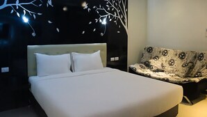 Ein modernes Schlafzimmer mit einem großen Bett, einer Couch und einer Wand mit Baum-Motiv.