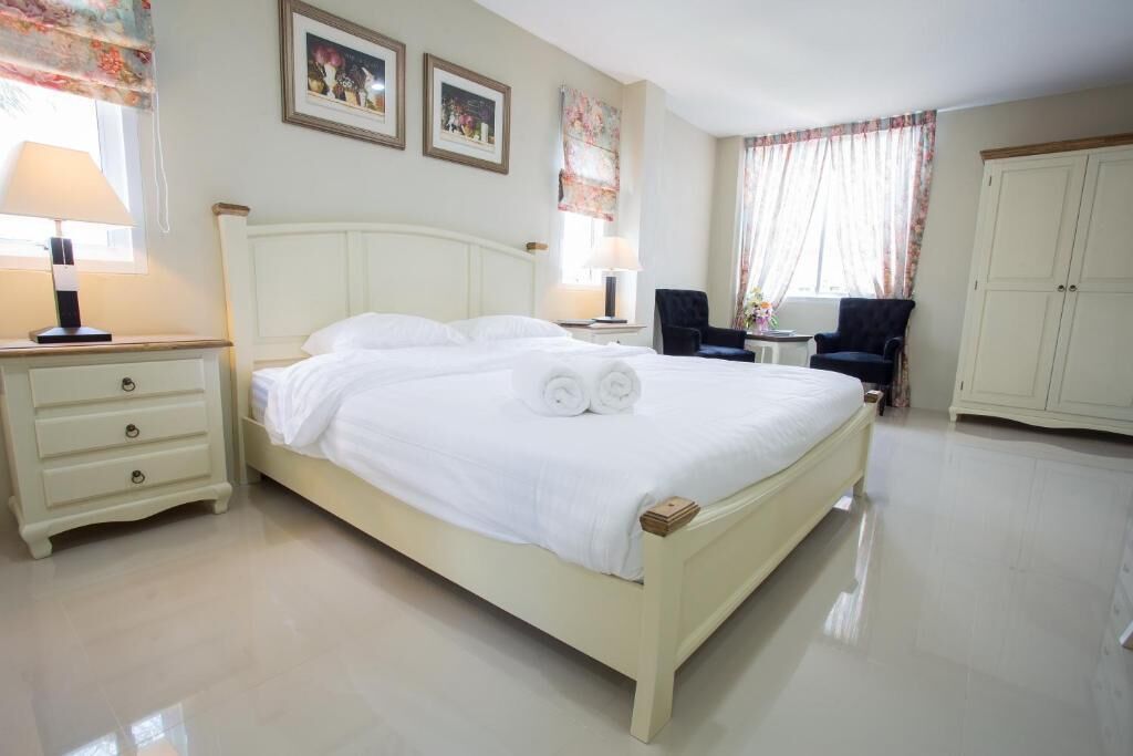A neatly arranged bedroom with a bed, bedside tables, a chair, and a wardrobe.