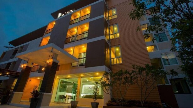 Um hotel de vários andares com design moderno, com varandas, janelas amplas e uma entrada bem iluminada.